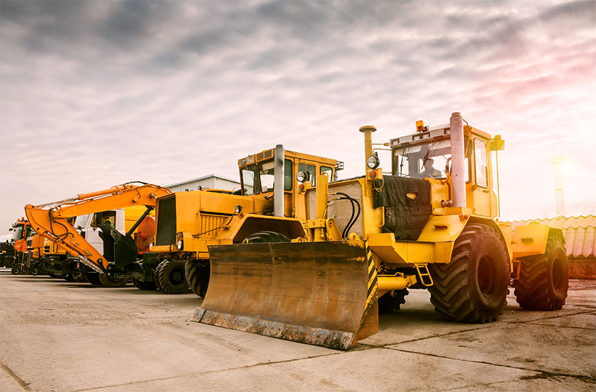 a line of heavy machinery including bulldozers and diggers