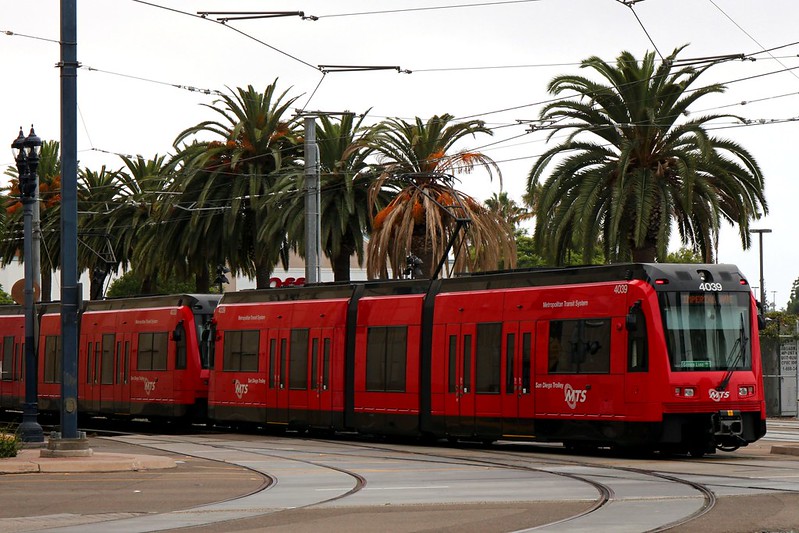 san diego metropolitan transit system trolley with palm trees in the background