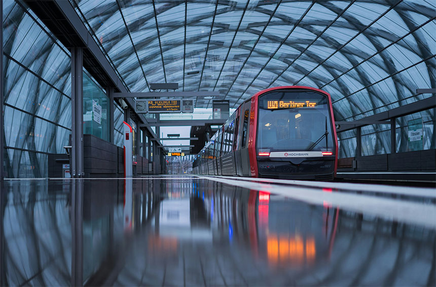 light-rail train stopped at a station with digital signage showing the next train is due